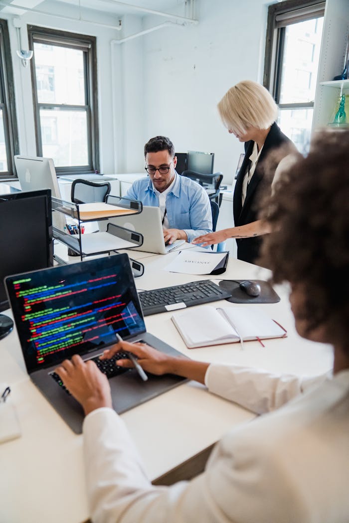 Team of professionals collaborating in a modern office, focused on coding and project management.